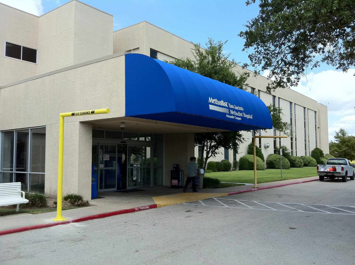 Hospital entrance with blue awning and trees.