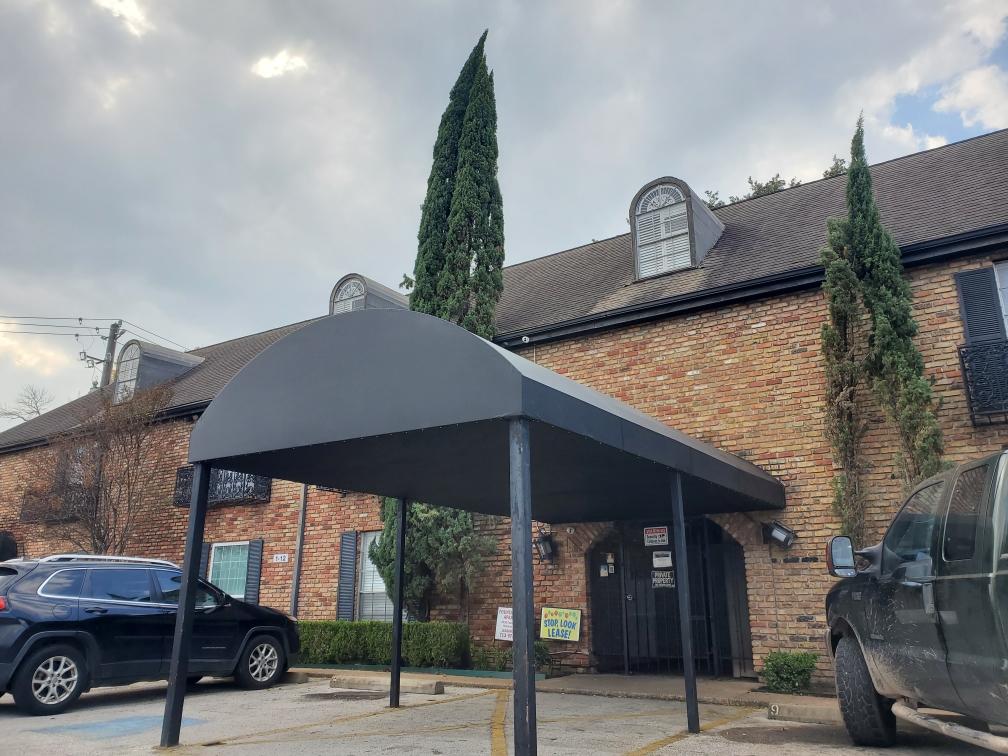 Brick building with arched entrance and cars.