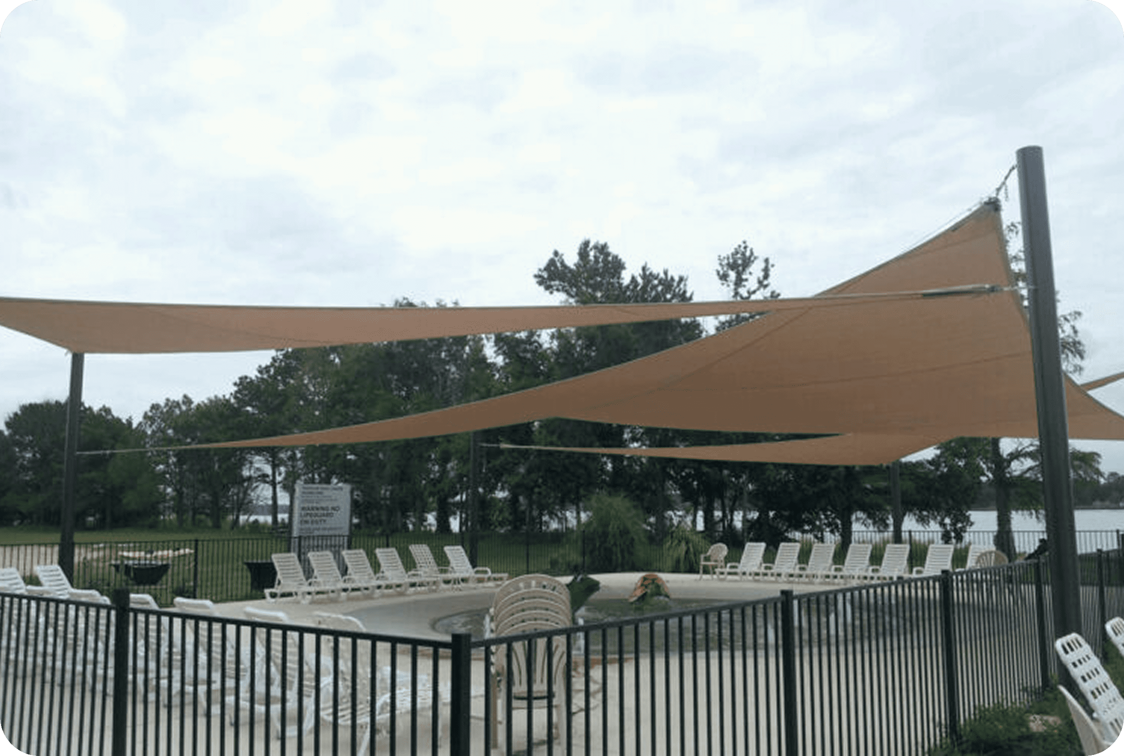 Poolside area with shade sails and chairs.